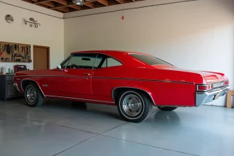 Chevrolet Impala 4 portes 1967 en rouge Bolero d'origine avec chromes d'usine, vue de profil dans un garage privé