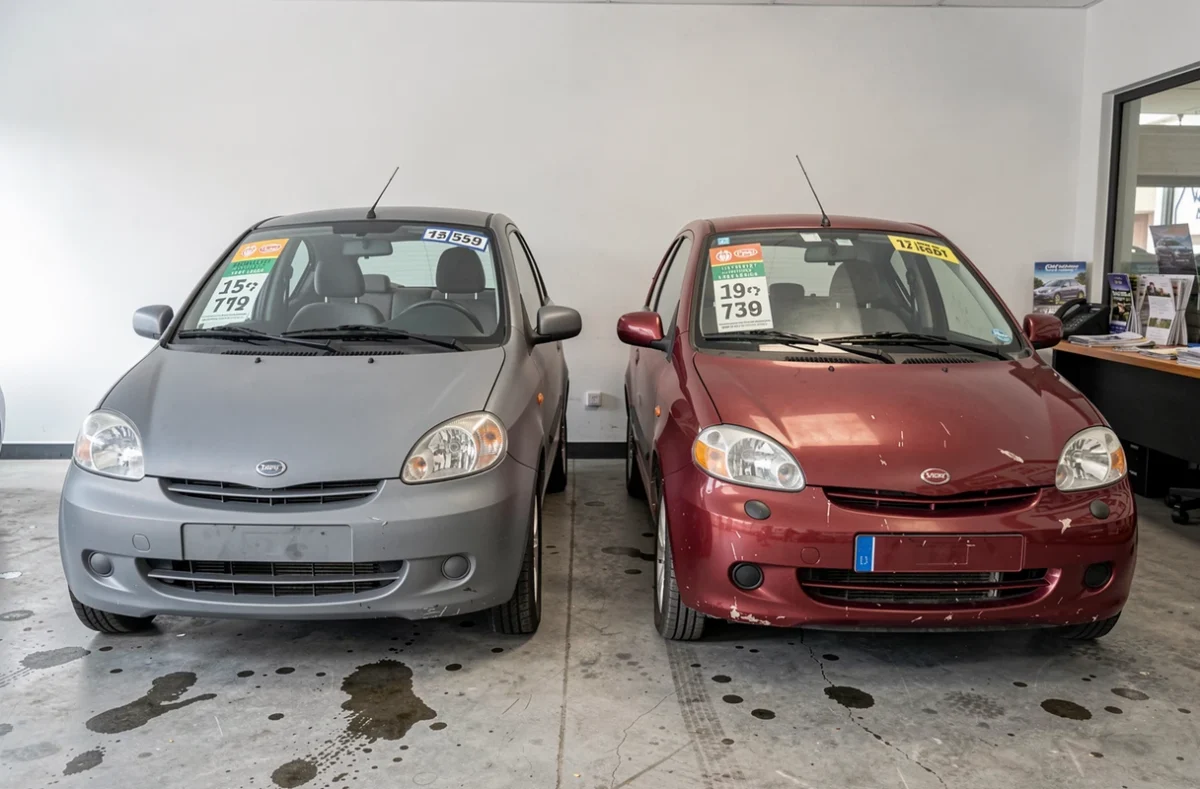 Deux voitures sans permis d'occasion exposées dans une concession automobile en banlieue parisienne avec étiquettes de prix