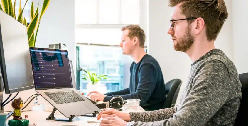 man sitting on chair wearing gray crew-neck long-sleeved shirt using Apple Magic Keyboard
