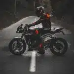 man in white and red jacket riding black sports bike on road during daytime
