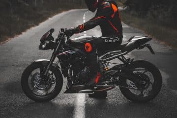man in white and red jacket riding black sports bike on road during daytime