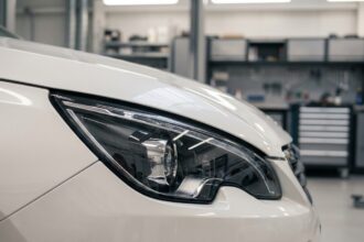 Phare avant LED Peugeot 308 en gros plan dans un atelier automobile, détail du projecteur et du bandeau lumineux