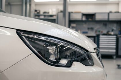 Phare avant LED Peugeot 308 en gros plan dans un atelier automobile, détail du projecteur et du bandeau lumineux