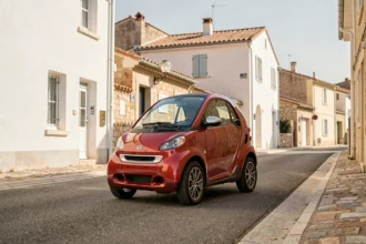 Voiture sans permis rouge garée dans une rue d'Aubagne avec architecture provençale en arrière-plan